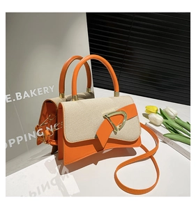 Detail of orange PU leather and beige woven fabric bucket bag with a golden D-shaped buckle