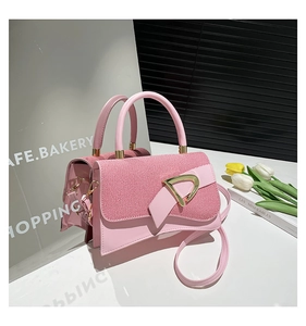 Detailed shot of pink textured crossbody bag with gold triangular metal buckle and handle