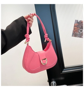 Détail du sac sous le bras rose avec boucle fer à cheval dorée et bandoulière nouée