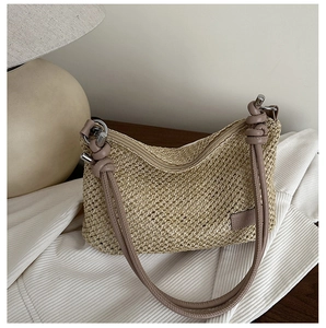 Détail d'un sac en paille tressée beige avec bandoulière en cuir noué et anneaux argentés