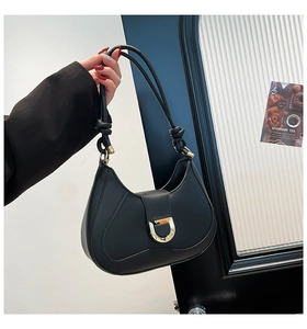Détail du sac à bandoulière noir en demi-lune avec boucle dorée et poignée nouée