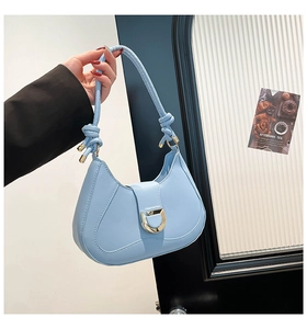 Détail du sac baguette bleu clair avec boucle en D dorée et poignée à nœuds décoratifs