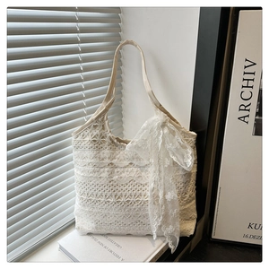 Detailed close-up of white lace tote bag featuring intricate hollow crochet and side bow