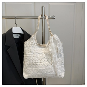 Detail of delicate white lace tote bag featuring a large bow and floral pattern