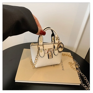 Nahaufnahme einer weißen Mini-Tasche aus Leder mit goldener Kette in der Hand gehalten