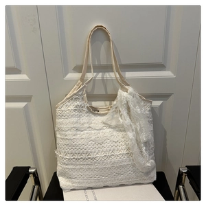Detailed close-up of white lace tote bag featuring multi-layered floral embroidery texture