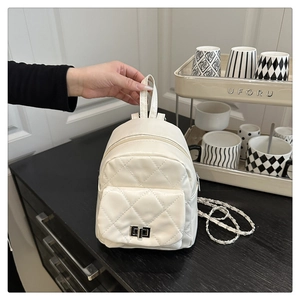 Detail of cream quilted mini backpack featuring silver twist-lock and chain strap