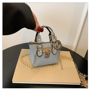 Nahaufnahme der hellblauen Mini-Umhängetasche mit Goldkette und Kiesellederstruktur