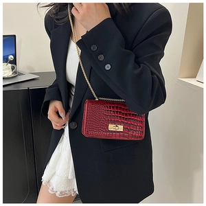 Macro detail of dark red croc-embossed crossbody bag with gold lock and chain strap