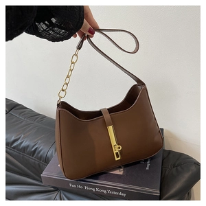Detail van een bruine leren tas met gouden metalen gesp en ketting schouderband