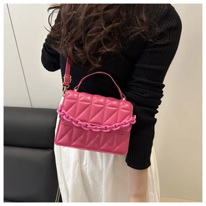Close-up of hot pink quilted crossbody bag with chunky chain and matte faux leather detail