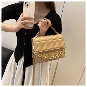 Detail of beige quilted rhombic crossbody bag with chunky plastic chain handle