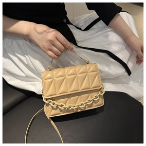 Detail of beige quilted flap bag with thick chain accent and adjustable shoulder strap