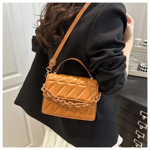 Detail of caramel quilted crossbody bag with textured chain and adjustable strap