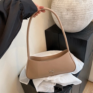 Minimalist beige crossbody shoulder bag with a silver metal bow accent in French style