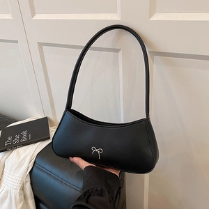 Minimalist black crescent armpit bag with silver bow accent in a stylish urban setting