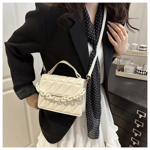 Detail of cream crossbody bag featuring triangle quilting and matte chain strap