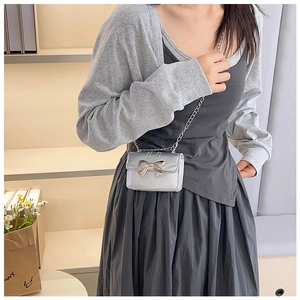 Detail shot of mini silver crossbody bag with metallic bow and elegant chain strap