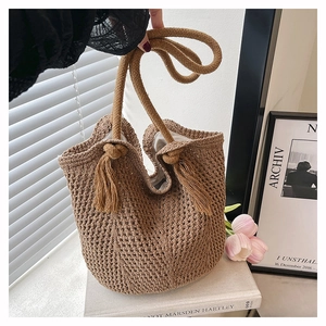 Detail of earthy brown woven knit bag with rustic rope handles and tassel accent