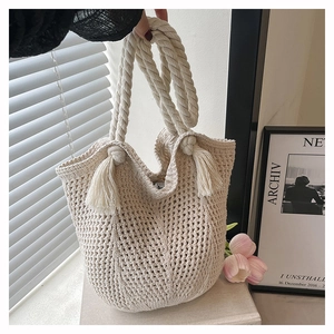 Detail of crochet tote bag featuring thick cotton rope handles and tassel decorations