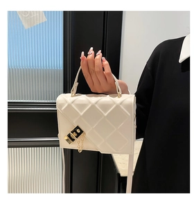 Detail of elegant off-white quilted handbag with asymmetric flap and gold chain lock