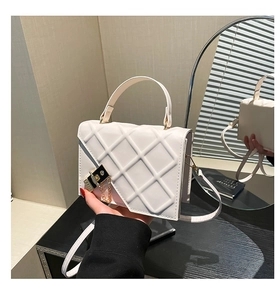 Detailed view of white quilted crossbody bag with gold metal clasp and chain strap