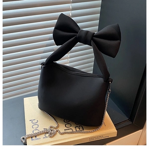 Detail of black bow handle handbag with silver chain strap on vintage books
