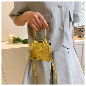 Detail of metallic gold mini bag with crocodile texture and structured handle