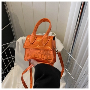 Detail of bright orange faux crocodile skin texture on a mini metallic crossbody handbag