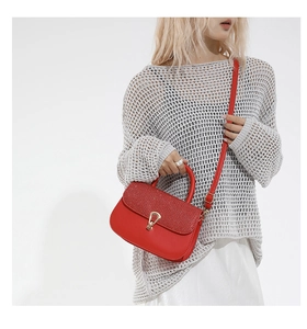Détail d'un sac rouge avec rabat pailleté et fermoir rotatif en métal doré