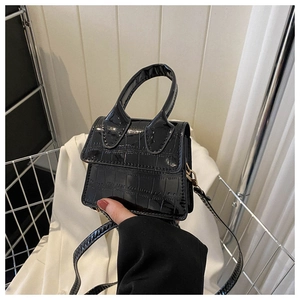 Close-up of black crocodile pattern patent leather mini bag with handle and strap