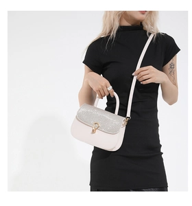 Détail d'un sac à bandoulière blanc élégant avec paillettes argentées et boucle en U dorée