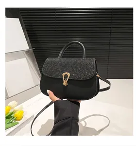 Détail du sac à main mat noir avec rabat pailleté et boucle métallique dorée chic