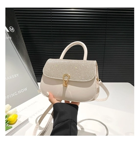 Détail d'un sac en cuir crème orné de strass argentés avec fermoir métallique doré chic