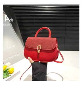 Détail du sac rouge avec texture pailletée et boucle dorée en forme de fer à cheval