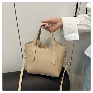 Detail shot of beige lychee pattern leather bucket bag with golden metal hardware