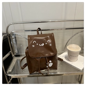 Detail of a brown PU leather backpack featuring a cute cat face and drawstring closure
