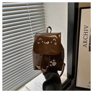 Detail of dark brown glossy patent leather backpack with cute white cat face and paw print