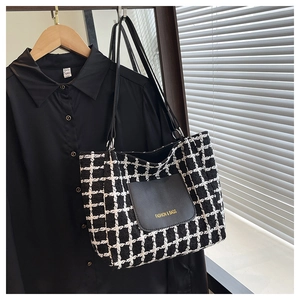 Dettaglio della borsa tote in tweed bianco e nero con tasca in pelle e manici