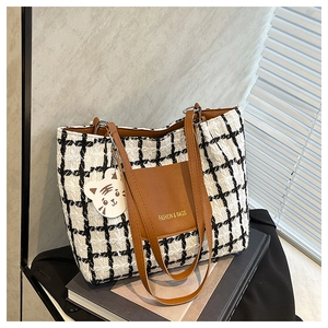Dettaglio della borsa tote in tweed a scacchi con cinturini in pelle e ciondolo a tigre