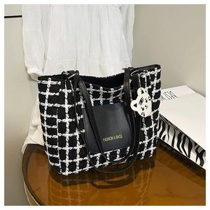 Detail of checkered tote bag with leather pocket and cute white cat keychain charm