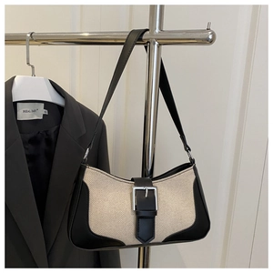 Detail of vintage canvas underarm bag with black leather trim and decorative metal buckle
