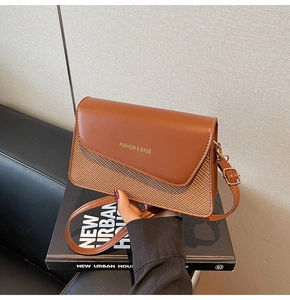 Detail of caramel crossbody bag featuring woven texture and fashion logo in a lifestyle shot