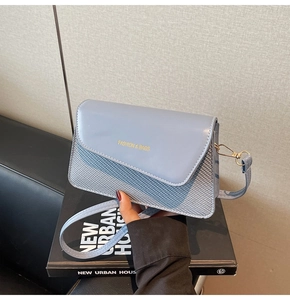 Detail of gray-blue crossbody bag featuring smooth leather and woven texture mix