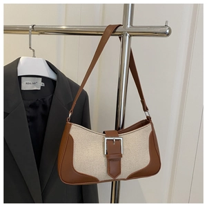 Detailed macro view of the canvas and leather patchwork underarm bag with silver buckle