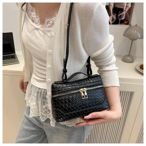 Detail shot of black woven leather vanity bag with top handle and metal zippers