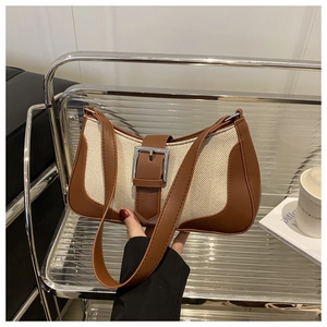 Detail of canvas shoulder bag with brown leather trim and silver metal buckle