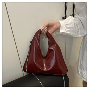 Detail einer dunkelroten Lacklederhandtasche mit Silberkette und glänzendem Finish