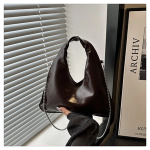 Close-up of glossy dark leather handbag with elegant silver metal chain strap detail