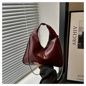 Detailed view of dark red glossy leather shoulder bag with a silver chain strap